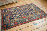 Antique Caucasian rug corner detail, intricate geometric borders, dark navy blossom motif.