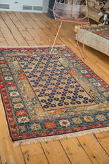 Detail of antique Caucasian rug: navy blossomed flower lattice on camel field with geometric borders.