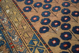 Detail of antique Caucasian rug, showing dark blue blossomed flower motif, geometric camel border, and even pile wear.
