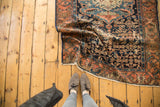 Folded antique Malayer rug, displaying intricate Herati motif in indigo and madder red.