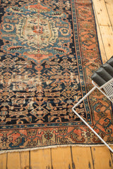 Corner of antique Malayer rug, showcasing intricate Herati motif, madder red border, and visible wear.