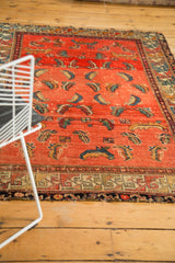 Antique Hamadan rug's geometric border, faded rose field, and colorful mahi motifs.