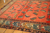 Antique Hamadan rug's geometric border, floating Mahi patterns, and visible worn edge.