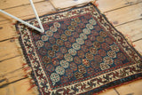 Antique Afshar bag face rug with indigo blue, wine red gul motifs, ivory border, and worn fringes.