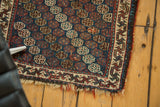 Antique Afshar rug's geometric border and repeating gul motifs, with worn pile and fringed edge.