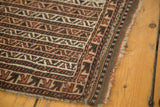 Belouch Bag Face rug corner, geometric banded pattern in browns, ivory, and camel with a tattered edge.