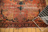 Antique Farahan Sarouk carpet corner with blush red field, navy vinery, and tattered fringe.