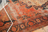 Antique Farahan Sarouk carpet section revealing threadbare blush field and intricate navy floral border.