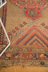 Antique Caucasian rug's tattered bottom edge, with blush, camel, navy rectilinear patterns.