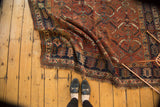 Folded vintage Kamseh rug showing madder root red, navy border, and Herati patterns.
