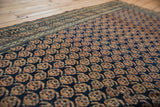 Intricate antique ivory boteh motifs and stylized border on a navy Caucasian rug.