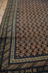 Angled detail of the antique Caucasian runner's dark boteh field and abrashed powder blue border.