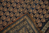 Detail of repeating boteh motif on navy field, revealing ornate Caucasian rug border.