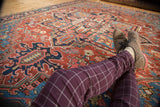 Antique Heriz carpet section: brick red field, vivid blue spandrel, floral motifs, abrashes.
