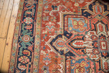 Antique Heriz carpet corner, navy spandrel and brick red field, with jewel-toned geometric motifs.