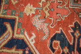 Antique Heriz carpet detail: brick red, navy field with speckled ivory and mallard green motifs.