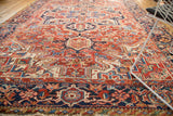 Vintage Heriz carpet with intricate vinery, floral motifs, cherry red field, and navy blue border.