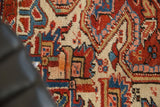 Hand-knotted Heriz rug detail: intricate vinery, floral motifs in cherry red, navy, beige.