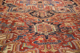 Intricate cherry red, navy blue, and beige motifs on vintage Heriz carpet.