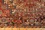 Vintage Heriz carpet's navy blue border and cherry red field with intricate geometric patterns.