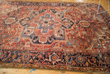 Intricate navy, red, and gold border design on vintage Heriz carpet corner with overcast end.