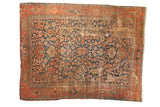 Antique Heriz carpet with indigo blue field, terracotta border, stylized geometric design, and surface wear.