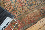Antique Heriz rug with textured low pile, geometric vinery, and time-softened hues.