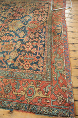 Patinated edge of antique Heriz carpet, showcasing stylized motifs in terracotta, indigo, and seafoam.