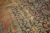 Antique Heriz carpet with indigo and rust stylized vinery, highlighting its distinct low pile and aged texture.