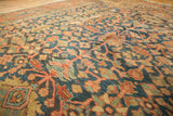 Intricate indigo and terra cotta floral vinery on an antique Heriz rug, showing aged pile.