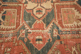 Visible wear showing geometric vinery and serrated leaves on vintage Heriz carpet.