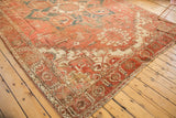 Vintage Heriz carpet corner with geometric border, faded terra cotta, ivory, and teal patterns.