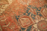 Vintage Heriz rug's bold geometric vinery, oversized palmettes in terra cotta, faded navy, ivory.