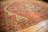 Faded madder root red and geometric vinery on a worn vintage Heriz carpet corner.