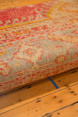 Unique antique Turkish rug fragment on ottoman side with faded pink, gold, and soft aqua motifs.