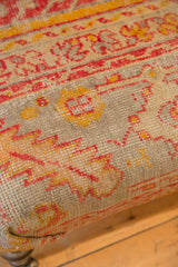 Detail of hand-knotted antique Turkish rug pattern featuring faded pink and yellow geometric motifs.