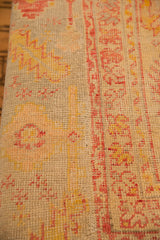 Close-up of antique Turkish rug fragment, highlighting hand-knotted pile and harmonious pink, yellow, aqua patterns.