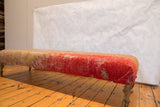 Textured antique Turkish rug fragment with pink and yellow hues on the ottoman.