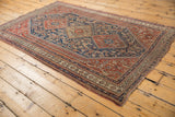 Antique Qashqai rug corner, displaying intricate indigo Herati pattern and chestnut borders.