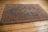 Fine antique Qashqai rug with indigo blue medallions, intricate Herati field, and visible age-related wear.