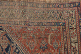 Close-up of finely woven Qashqai rug pile, showing indigo, wine red Herati motif and wear.
