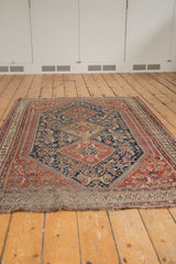 Tattered fringe and patterned end border of an antique Qashqai rug with sand, red, and indigo.