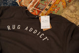 Branded Rug Addict hang tag on the collar of a gunpowder long sleeve t-shirt.