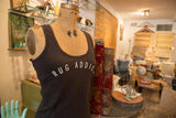 Rug Addict tank top styled on a vintage mannequin beside rolled antique rugs.
