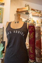 Gunpowder gray Rug Addict tank top on a vintage mannequin beside rolled antique rugs.