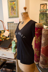 Women's black Rug Addict t-shirt on a mannequin beside rolled vintage rugs.
