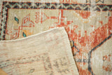 Close-up of folded vintage distressed Oushak rug showing worn red pile and woven back.