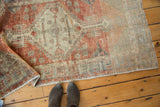 Distressed Oushak rug displaying faded brick red geometric stylization and mostly even pile wear.