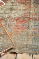 Close-up of distressed vintage Oushak rug, faded brick red and ivory tones, worn pile.
