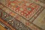 Distressed texture of a vintage Oushak rug with brick red and beige geometric motifs.